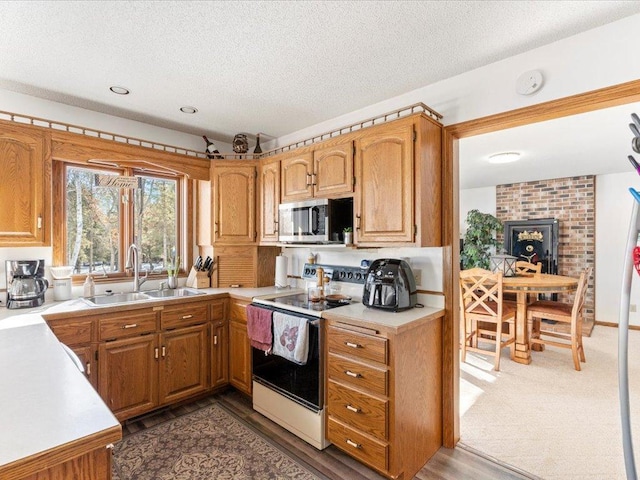 kitchen with a sink, stainless steel microwave, a textured ceiling, electric range oven, and light countertops