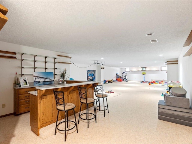 bar with visible vents, light carpet, a textured ceiling, and a dry bar