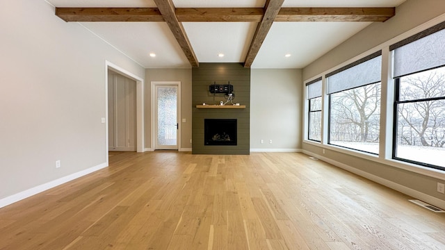 unfurnished living room with baseboards, a fireplace, visible vents, and light wood-style floors