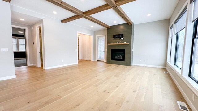 unfurnished living room with visible vents, baseboards, light wood-style floors, a fireplace, and beam ceiling