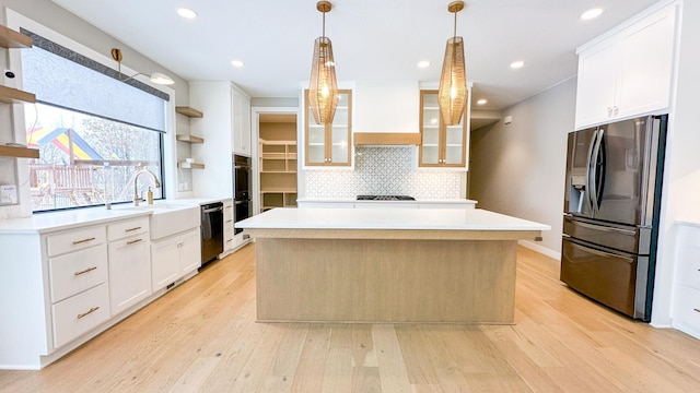 kitchen with black dishwasher, custom range hood, stainless steel refrigerator with ice dispenser, open shelves, and a sink