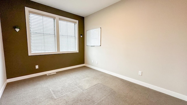 carpeted spare room with visible vents and baseboards