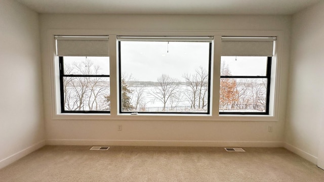 spare room with light colored carpet, visible vents, and baseboards