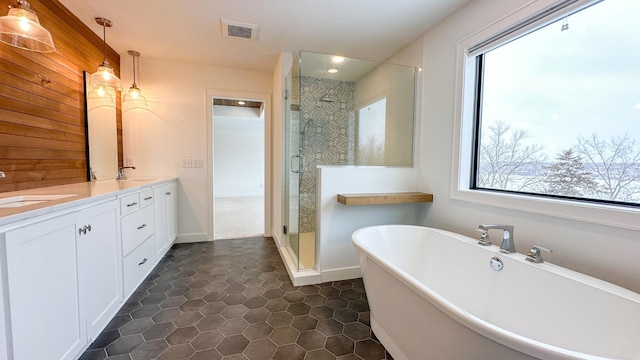 bathroom with double vanity, visible vents, a soaking tub, a shower stall, and a sink