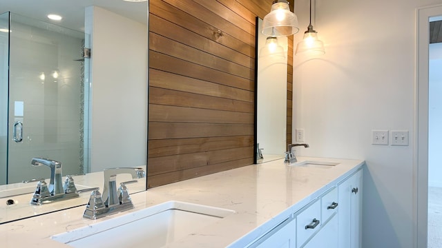 bathroom with double vanity, a stall shower, and a sink