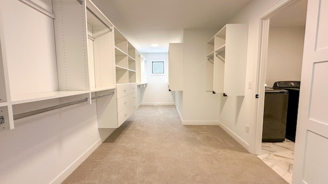 walk in closet featuring washer / dryer and light colored carpet