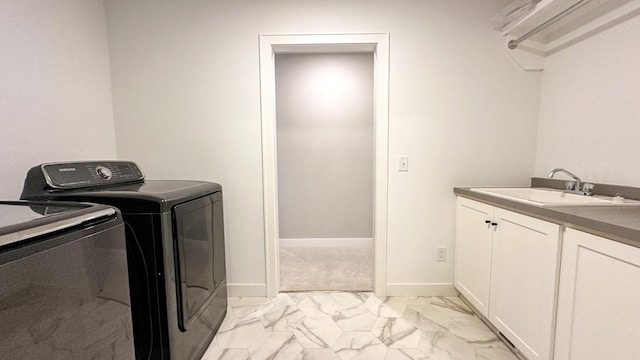 laundry room with cabinet space, baseboards, marble finish floor, washing machine and dryer, and a sink