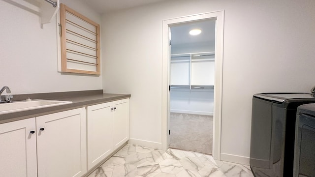 laundry room featuring cabinet space, baseboards, marble finish floor, washer and dryer, and a sink