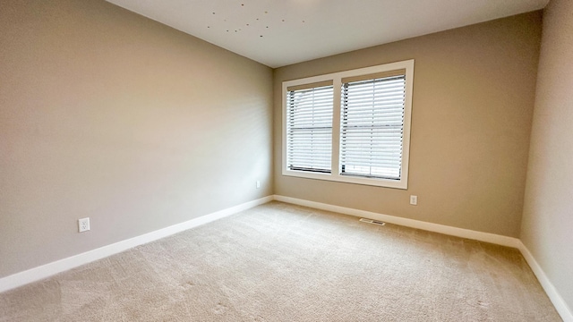 unfurnished room featuring lofted ceiling, light carpet, visible vents, and baseboards