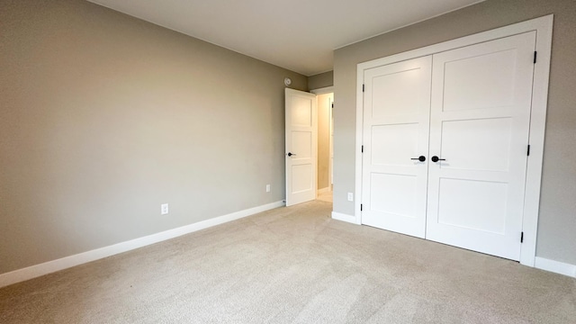 unfurnished bedroom with light carpet, baseboards, and a closet