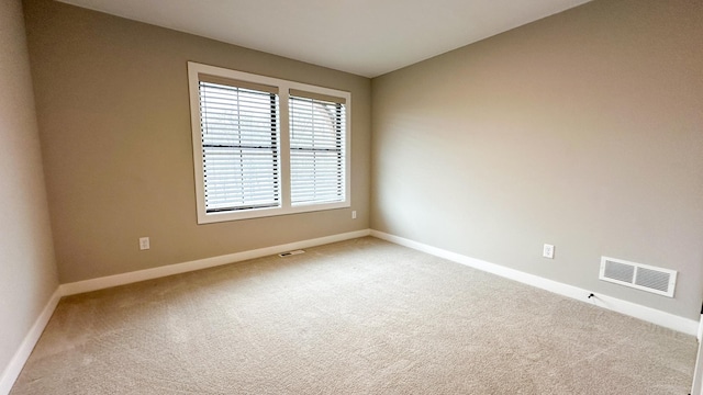 carpeted spare room featuring visible vents and baseboards