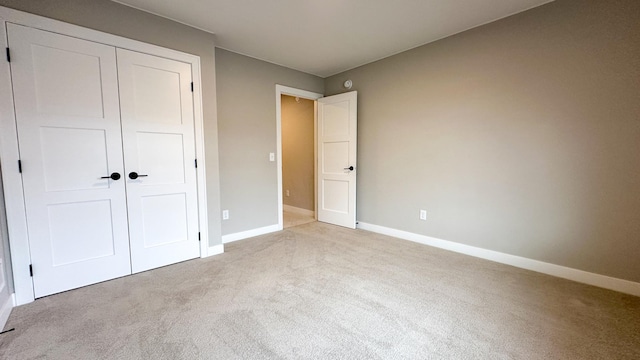 unfurnished bedroom with a closet, carpet flooring, and baseboards