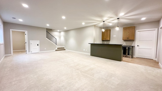 unfurnished living room with wine cooler, recessed lighting, light carpet, bar, and stairs