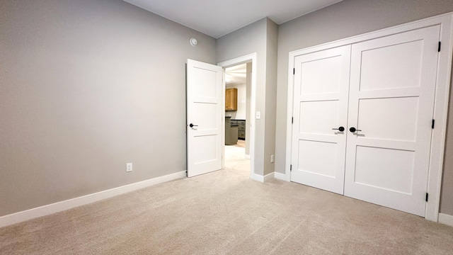 unfurnished bedroom with baseboards, a closet, and light colored carpet