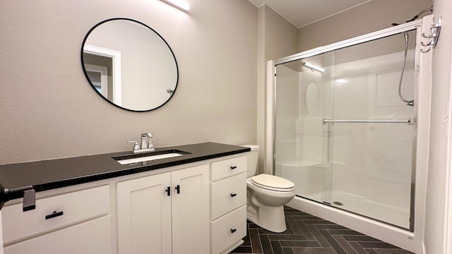 bathroom featuring toilet, a stall shower, and vanity