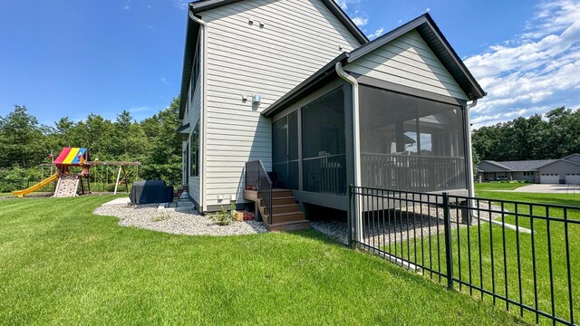 back of property with a sunroom, a playground, fence, and a lawn