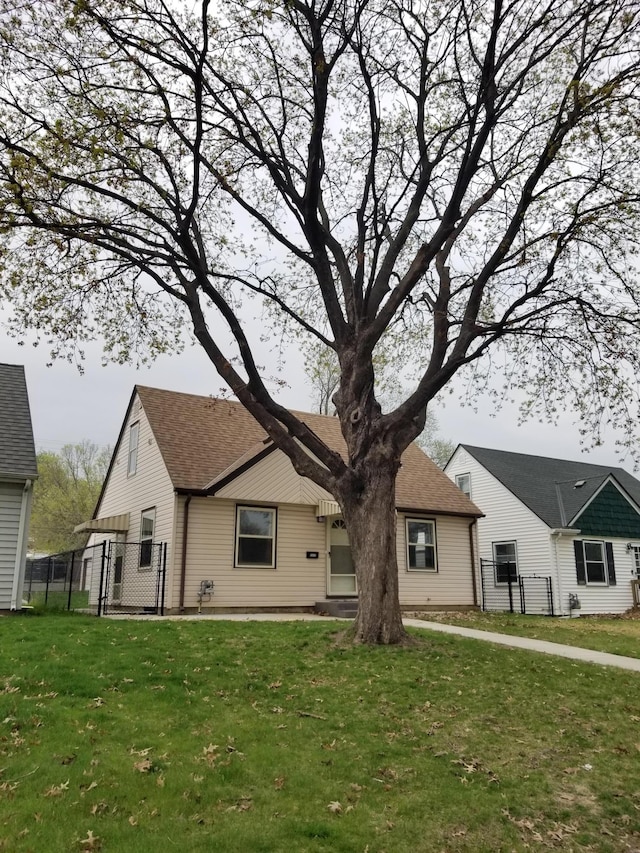 view of front facade with roof with shingles, fence, and a front lawn