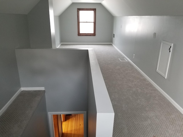 additional living space featuring carpet floors, visible vents, vaulted ceiling, and baseboards