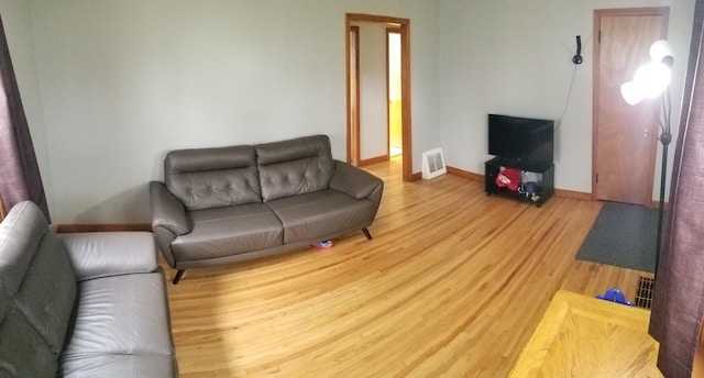 living area featuring baseboards, visible vents, and wood finished floors