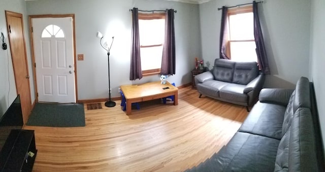 living room with baseboards, wood finished floors, visible vents, and a healthy amount of sunlight