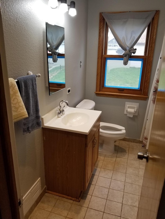 half bath with visible vents, baseboards, toilet, tile patterned flooring, and vanity