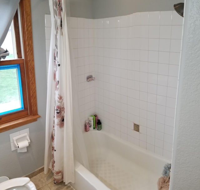 full bath with shower / tub combo, a healthy amount of sunlight, baseboards, and tile patterned floors