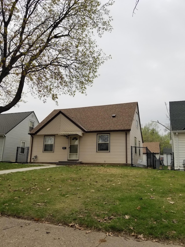 view of front of property featuring a shingled roof, a front yard, fence, and a gate