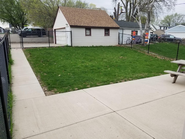 view of yard with a detached garage, fence, and an outbuilding