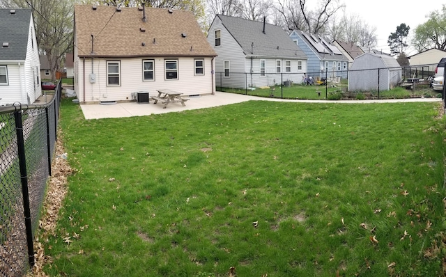 back of house with a fenced backyard, a shingled roof, a yard, a residential view, and a patio area