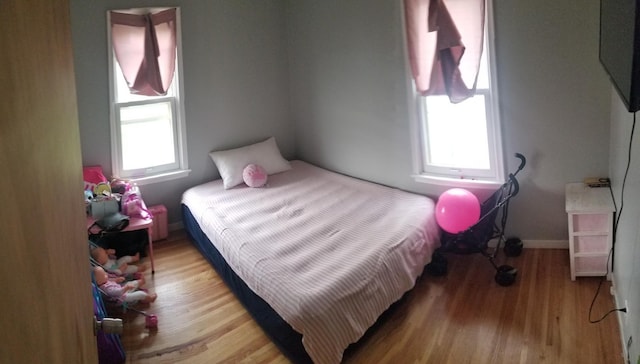 bedroom with light wood finished floors, multiple windows, and baseboards