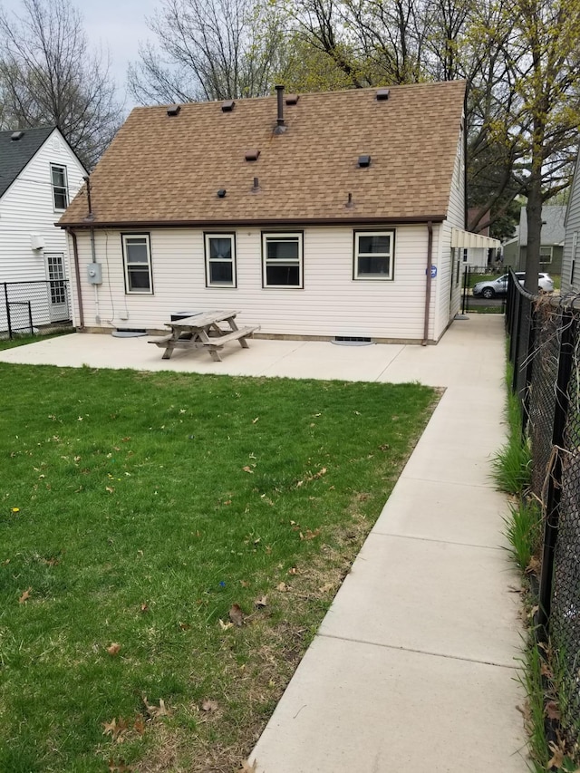 rear view of property featuring a patio area, a fenced backyard, a lawn, and roof with shingles