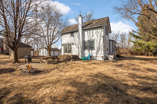 back of house with an outbuilding, an outdoor fire pit, and a chimney