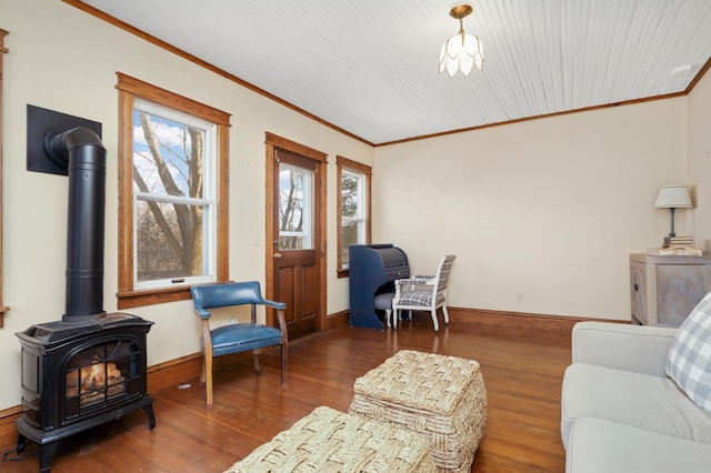 living room with ornamental molding, a wood stove, baseboards, and wood finished floors