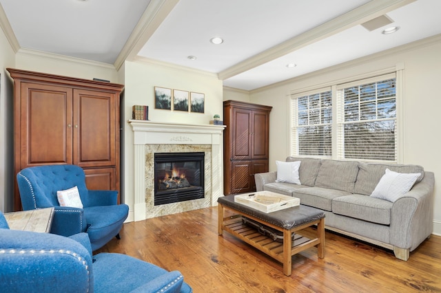 living area with recessed lighting, crown molding, light wood-style flooring, and a premium fireplace