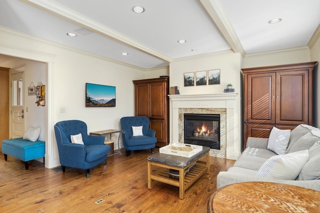 living room with beam ceiling, a fireplace, recessed lighting, light wood-style flooring, and ornamental molding