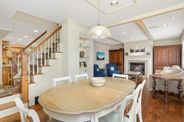 dining space featuring a glass covered fireplace, stairway, hardwood / wood-style floors, crown molding, and built in shelves