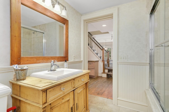 bathroom featuring a wainscoted wall, tile patterned flooring, a shower with door, and vanity