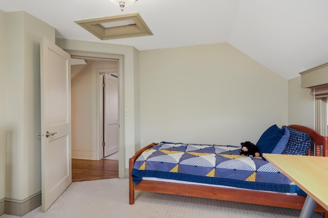 bedroom featuring lofted ceiling, attic access, and light colored carpet