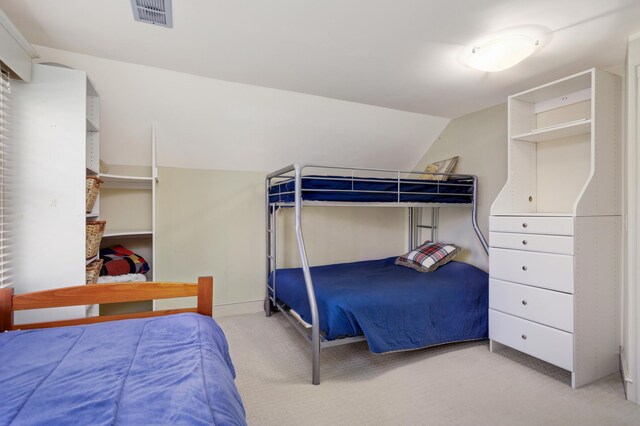 bedroom with visible vents, vaulted ceiling, and carpet flooring