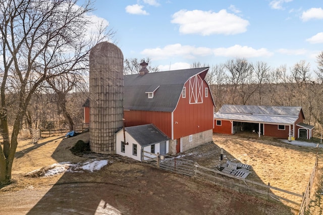 exterior space with a barn, a gambrel roof, a chimney, an outbuilding, and fence