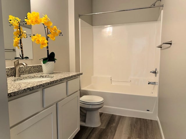 bathroom featuring baseboards, toilet, wood finished floors, vanity, and washtub / shower combination