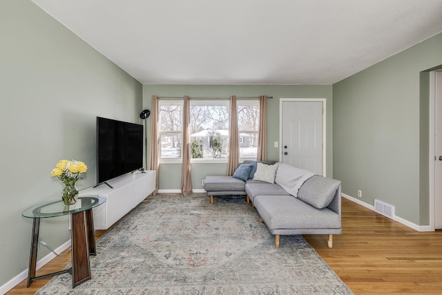 living room featuring visible vents, baseboards, and wood finished floors