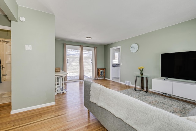 living area with light wood finished floors, visible vents, and baseboards