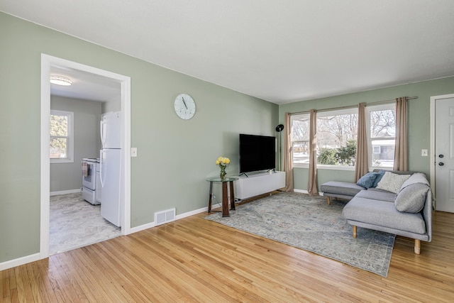 living area with visible vents, baseboards, and wood finished floors