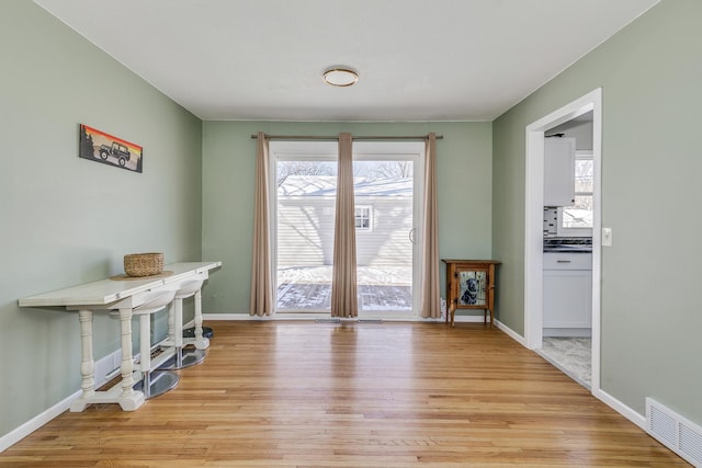 doorway to outside featuring baseboards, visible vents, and light wood finished floors