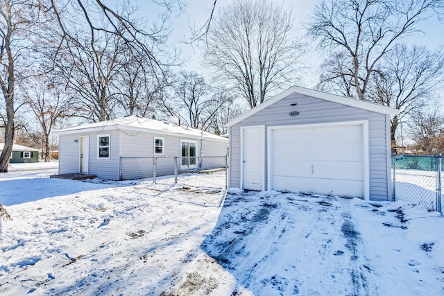 snow covered garage with a garage and fence