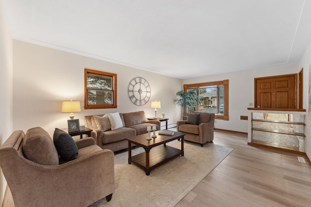 living room with a baseboard heating unit, light wood-type flooring, and baseboards