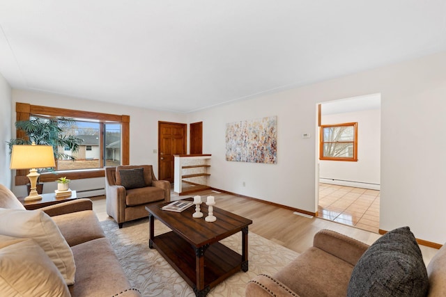 living room featuring a baseboard heating unit, light wood-type flooring, and baseboards