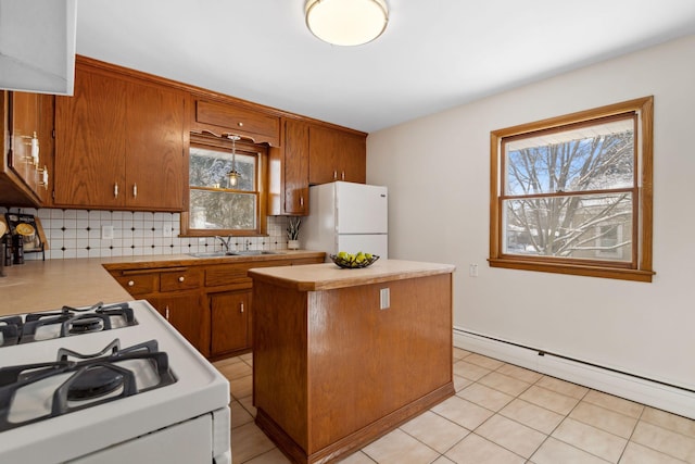 kitchen with white appliances, decorative backsplash, a center island, a baseboard heating unit, and a sink