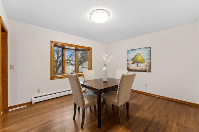 dining area with a baseboard radiator, a textured ceiling, baseboards, and wood finished floors